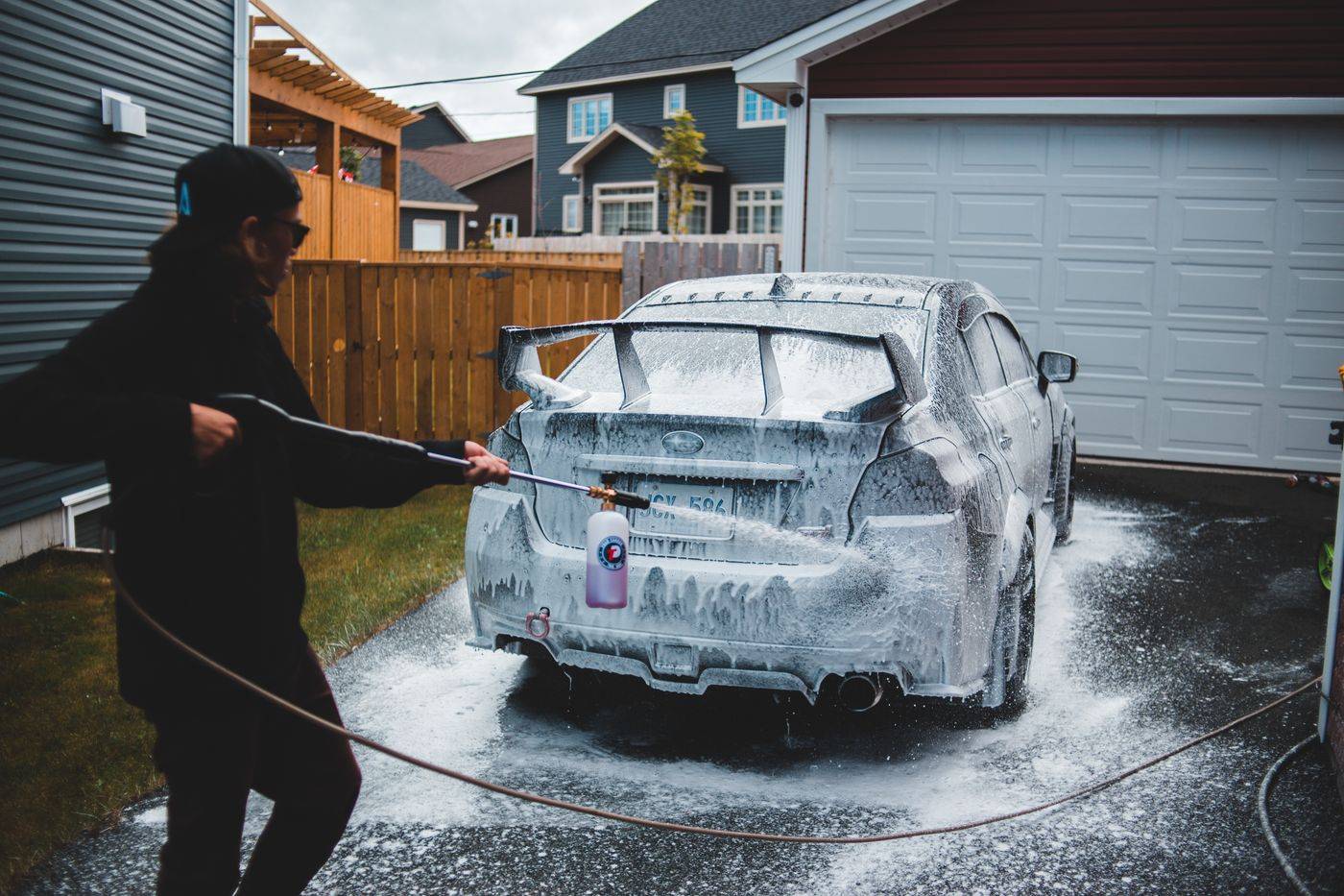 A car being foam washed in the driveway of a house
