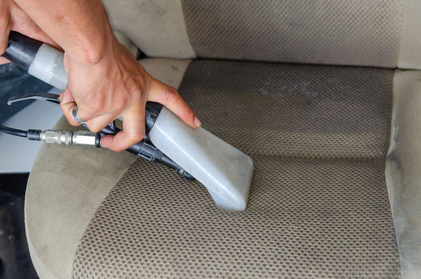 A cloth car seat being vacuumed